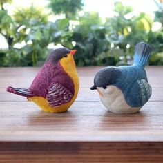 two small birds sitting on top of a wooden table