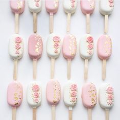 pink and white lollipops with gold sprinkles are arranged on sticks