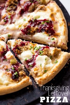 a pizza with cheese and cranberry sauce is cut into slices on a black platter