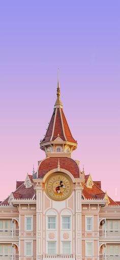 a large building with a clock on it's face in front of a pink sky