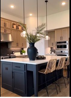 a large kitchen with an island in the middle and chairs at the end, along with lights hanging from the ceiling