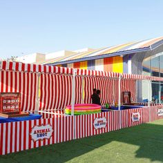 a large red and white striped tent sitting on top of a lush green field next to a building