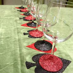 wine glasses lined up on a table with red and black coasters in the middle