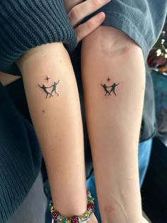 two people with matching tattoos on their arms, one is holding the other's arm