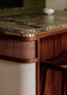 a counter top with a bowl on it next to two stools and a table