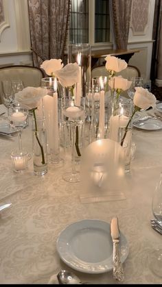 the table is set with white roses and candles