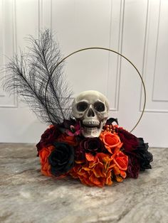 a skull sitting on top of a flower arrangement with black and orange flowers in it