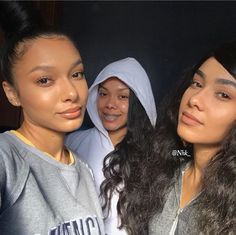 three women posing for the camera with one wearing a hoodie and another in a sweatshirt