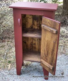 an old wooden cabinet with two doors and shelves on the bottom is sitting in gravel