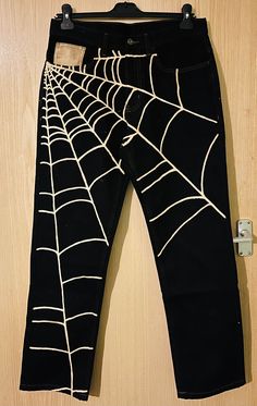 a pair of black jeans with spider webs on them