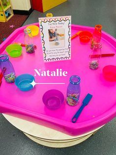 there is a pink tray with plastic cups and spoons on it that are labeled natalie