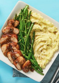 a plate with mashed potatoes, green beans and meat