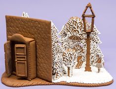 a gingerbread house with an open door and snow on the ground next to it