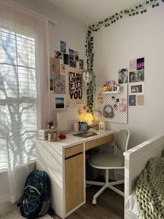 a bedroom with a bed, desk and chair next to a wall covered in pictures