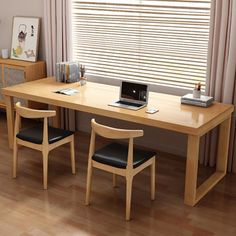 a wooden table with two chairs and a laptop computer on it in front of a window