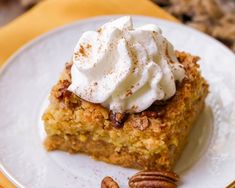 a piece of cake on a plate with whipped cream and pecans in the background