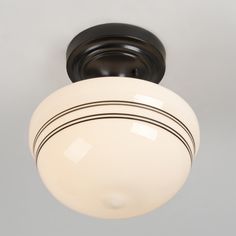 a ceiling light with a white glass shade on it's side and black trim around the rim