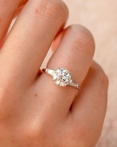 a woman's hand with a diamond ring on top of her finger and an engagement band