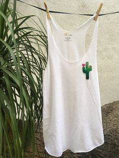 This ultra light and soft racer back tank top has been adorably decorated with a serape cactus (made out of real Mexican blanket!). The vibrant colors of serape catch the eye and add a necessary pop to an otherwise casual tank! These are perfect for a warm summer day or to layer under a cardigan after the sun goes down. Want the same cactus on a different color tank? Just message us! We are here to help and happy to take custom orders! Want to see more? Check out our shop! www.etsy.com/shop/kcal Casual Cotton Tank Top For Festivals, Cotton Racerback Tank Top For Vacation, Summer Cotton Racerback Tank Top, Summer Festival Cotton Tank Top, Spring Festival Racerback Tank Top, Casual White Top For Cinco De Mayo, White Tank Top For Festival, Mexican Blanket, Casual Tanks