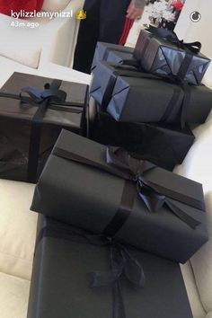 four black wrapped presents sitting on top of a white couch