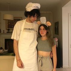 a man standing next to a woman wearing an apron and mouse ears on her head