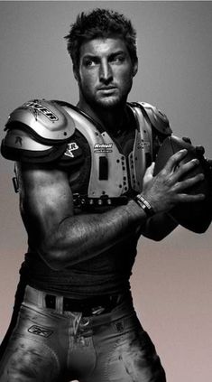 a black and white photo of a football player with his hands on his chest holding a ball