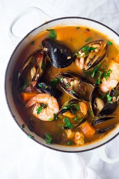 a pot filled with seafood and mussels on top of a white table cloth