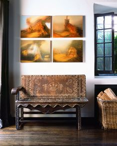 a wooden bench sitting in front of a window next to a wall with pictures on it