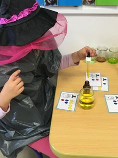 two children sitting at a table playing with some sort of liquid