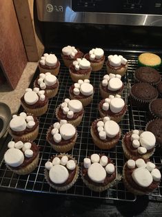 cupcakes with white frosting on top sitting on a cooling rack in front of an oven