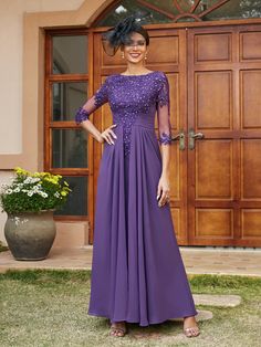 a woman standing in front of a door wearing a purple dress