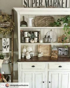 a white hutch filled with lots of items and decor on top of wooden shelves