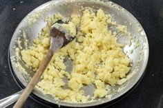 some food is cooking in a pan with a wooden spoon on the stove top next to it