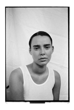 a black and white photo of a young man in tank top looking at the camera