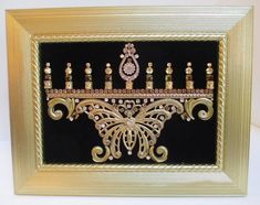 a gold and black framed art piece with candles in the shape of an ornate design