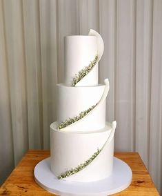 a three tiered white cake sitting on top of a wooden table