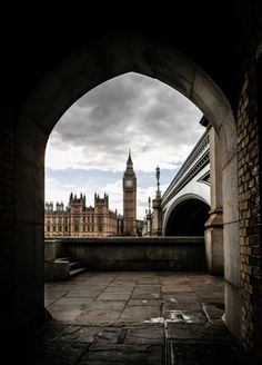 the big ben clock tower towering over the city of london from under an arched bridge