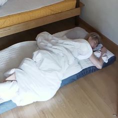 a woman laying on top of a bed in a bedroom next to a wooden floor