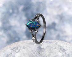 an opalite ring on top of a rock with clouds in the background and blue sky