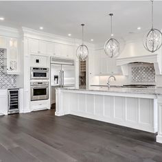 a large kitchen with white cabinets and marble counter tops