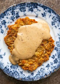 a blue and white plate topped with meat covered in gravy