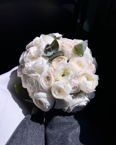 a bridal bouquet with white roses and greenery on the bride's lapel