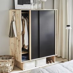 an open cabinet with clothes hanging on it