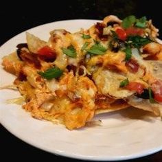 a white plate topped with nachos covered in cheese and toppings on top of tortilla chips