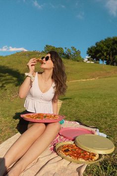 a woman sitting on the ground eating pizza