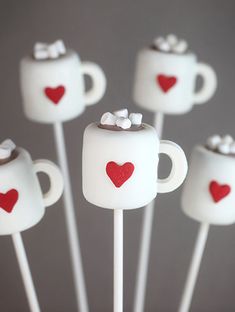 white marshmallows with red hearts and bows on them are arranged in the shape of mugs