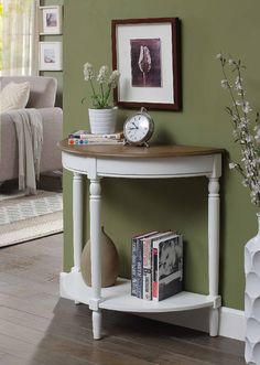 a corner table with a clock on it in front of a green wall and wooden floors