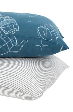 two pillows sitting next to each other on top of a pillow case with blue and white designs