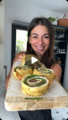 a woman holding a tray with food on it and smiling at the camera while she is showing off her sandwich