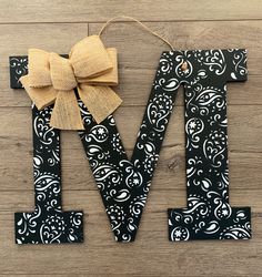 the letter m is made out of black and white fabric with a bow on it